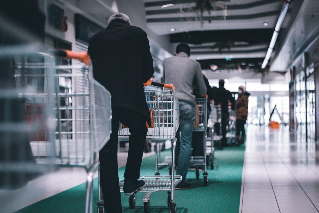 Shoppers with shopping carts lined up waiting to check out at a store.