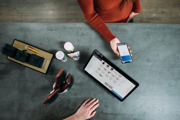 woman checking out at cash register using her smart phone