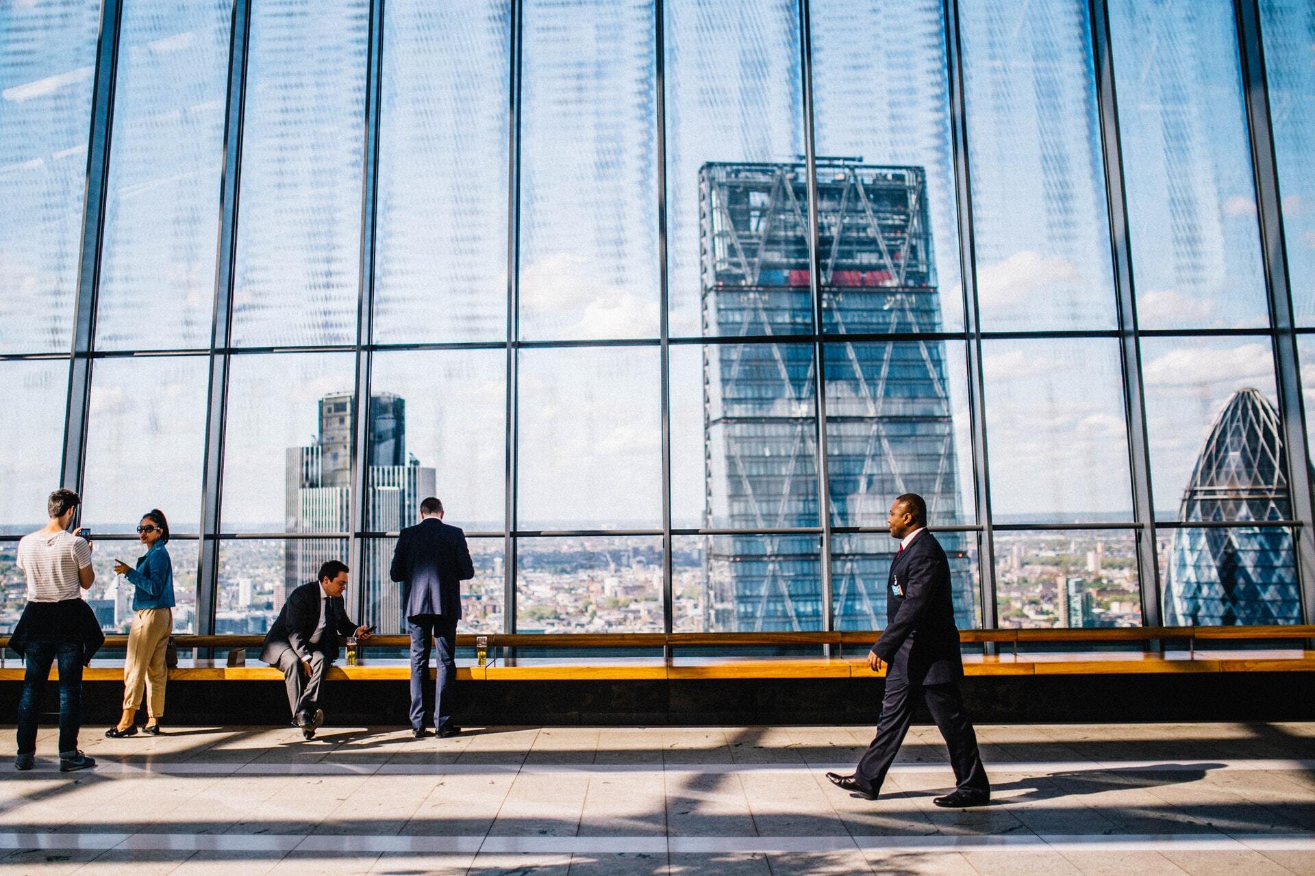 Picture of an man walking with tall office buildings behind him. 