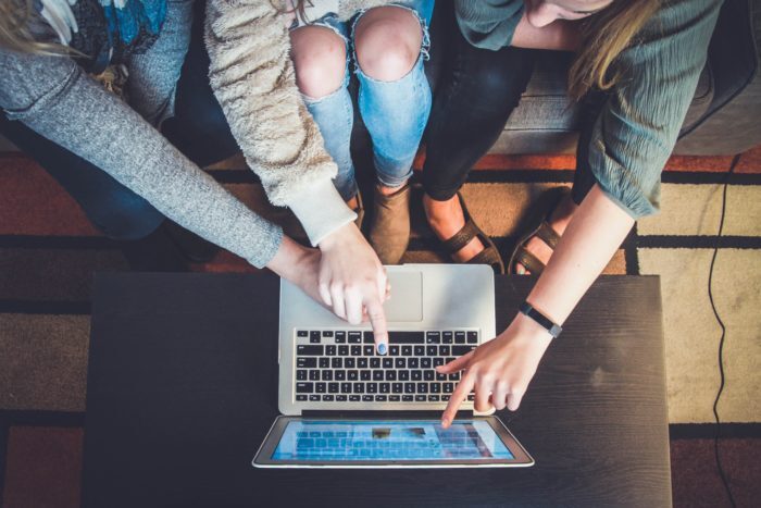 three people pointing at a laptop