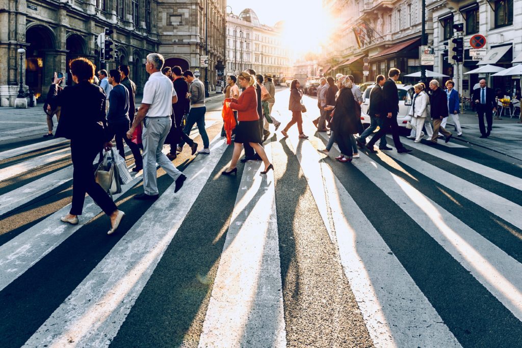 Crowd of people walking across a street.